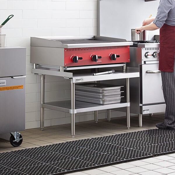 A woman using a Regency stainless steel equipment stand in a commercial kitchen.