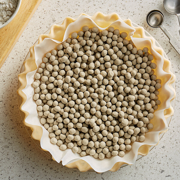 A bowl of Matfer Bourgeat ceramic pie weights on a white counter.