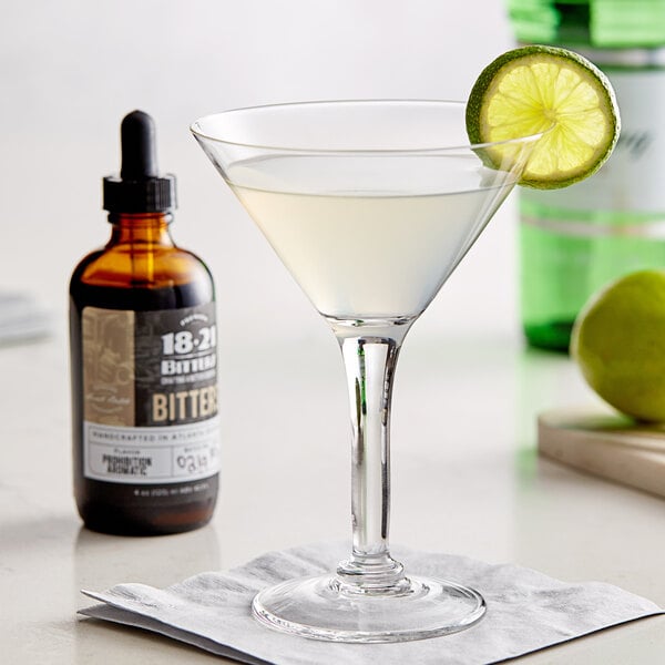 A bottle of 18.21 Bitters next to a martini with a lime wedge.
