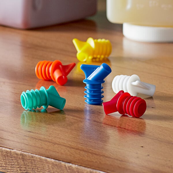 A table with colorful Vollrath Traex Bar Keep II plastic pour spouts.