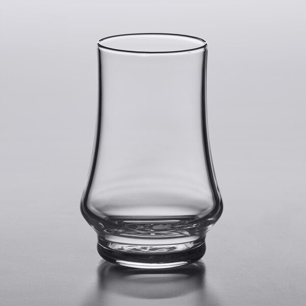 An Arcoroc Kenzie whiskey taster glass with a small amount of liquid in it.