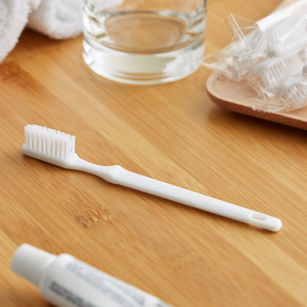 A white Novo Essentials travel toothbrush and toothpaste on a wood surface.