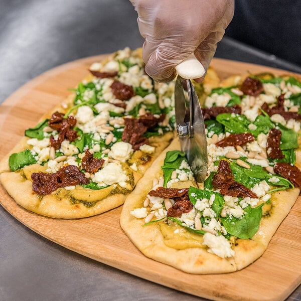 A person cutting a Rich's oval flatbread crust into slices with a knife.