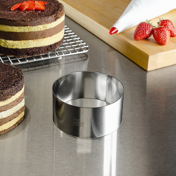 A stainless steel round cake in a Fat Daddio's metal ring mold on a table.