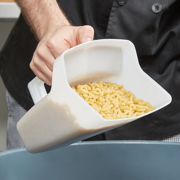 A person holding a Rubbermaid Bouncer Utility Scoop filled with pasta.
