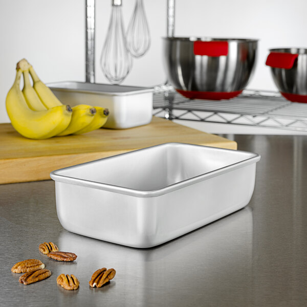 A silver rectangular metal pan with nuts and pecans on a counter.
