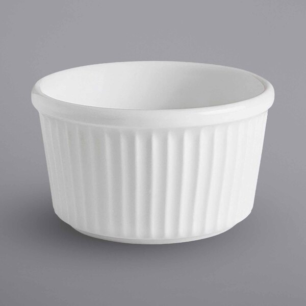 A close up of a Corona by GET Enterprises bright white fluted ramekin with a ribbed rim on a gray surface.