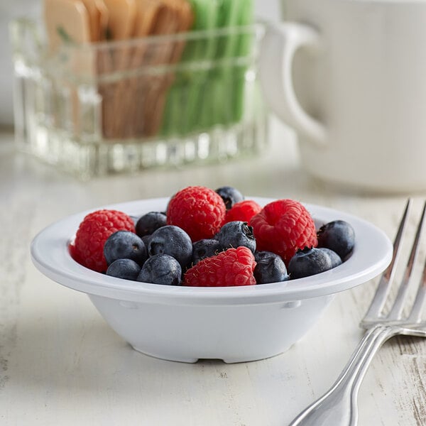 A white Acopa melamine fruit bowl filled with blueberries and raspberries with a fork.
