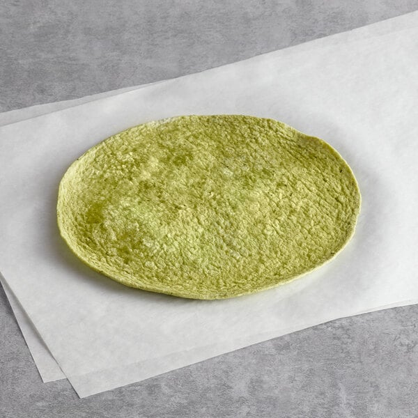 A Father Sam's Bakery Garden Spinach tortilla on white paper with a green leaf.