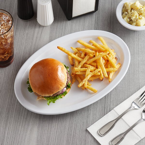 A white Acopa melamine oval platter with a hamburger and fries on it next to a glass of soda.