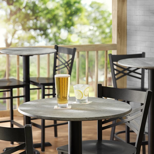 A table with two glasses of beer on it with a chair.
