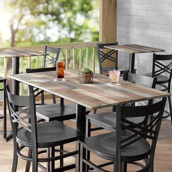 A Lancaster Table & Seating rectangular table top with a textured mixed plank finish on a porch with chairs and a plant.