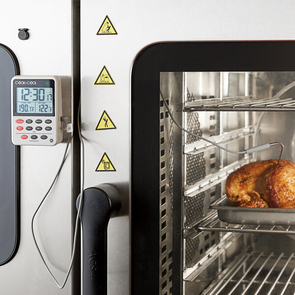 A close-up of a Cooper-Atkins digital thermometer in a chicken in an oven.