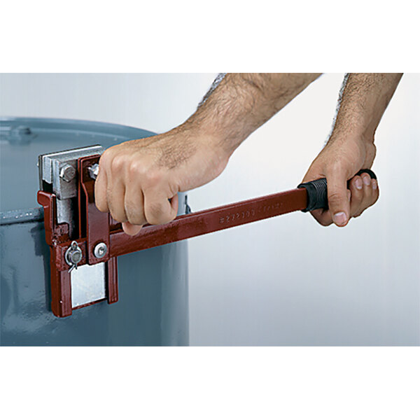 A hand holding a red metal bar with a metal latch on a Wesco Industrial Products Vertical Slide Drum Deheader.