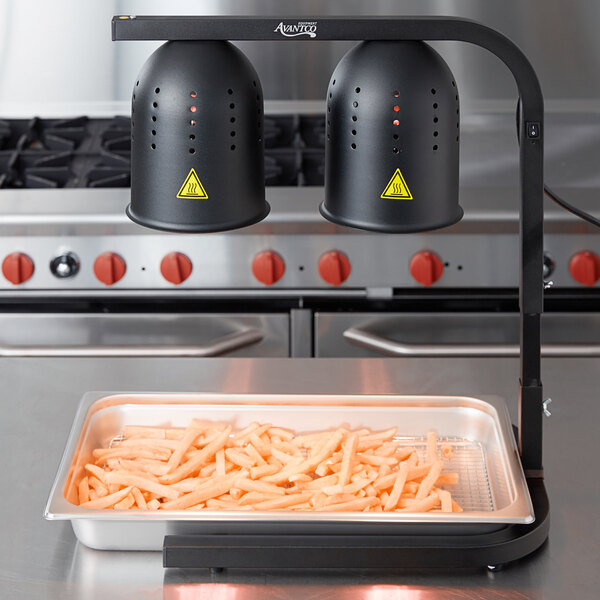 A tray of french fries with two black heat lamps over them.