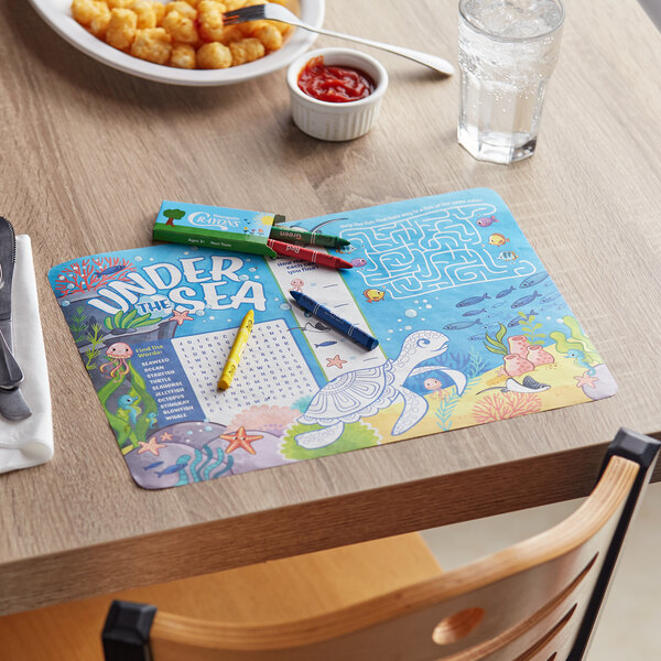 A table with a Choice Kids Under the Sea themed interactive placemat and triangular crayons.