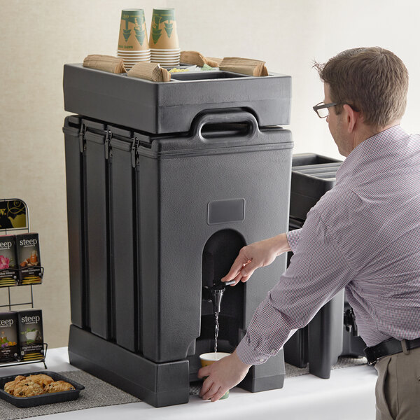A man using a Cambro insulated beverage dispenser to pour water.