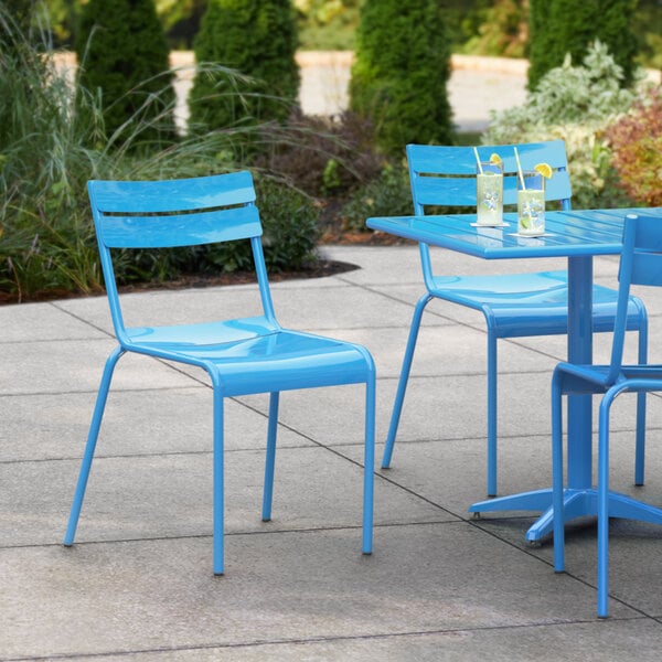 A blue Lancaster Table & Seating outdoor side chair at a table on a patio.