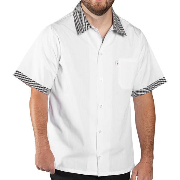 A man wearing a white Uncommon Chef cook shirt with Shepherd's check trim and black collar.