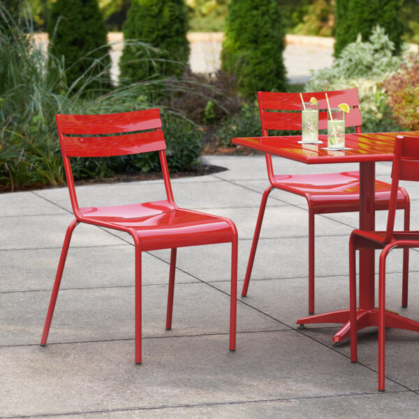 A red Lancaster Table & Seating outdoor side chair at a table on a patio.