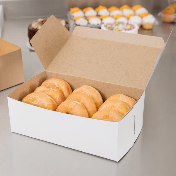 A white bakery box of donuts on a counter.