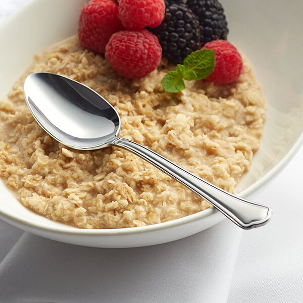 A bowl of oatmeal with berries and an Acopa stainless steel teaspoon.