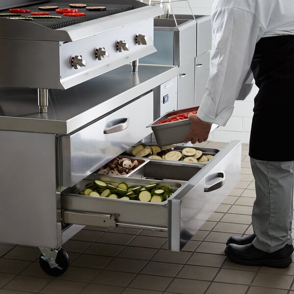 A person putting food into a Beverage-Air chef base drawer.