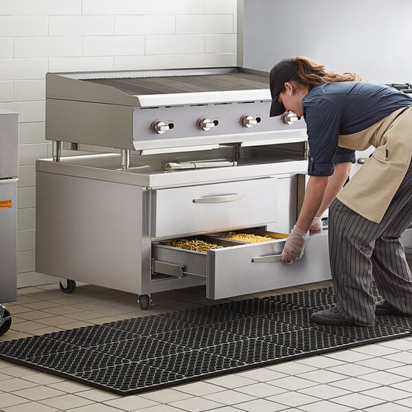 A woman opening a drawer in a Beverage-Air refrigerated chef base in a professional kitchen.