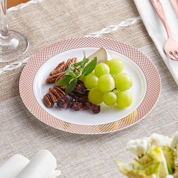 A Visions white plastic plate with a rose gold lattice design holding fruit, nuts and a fork.