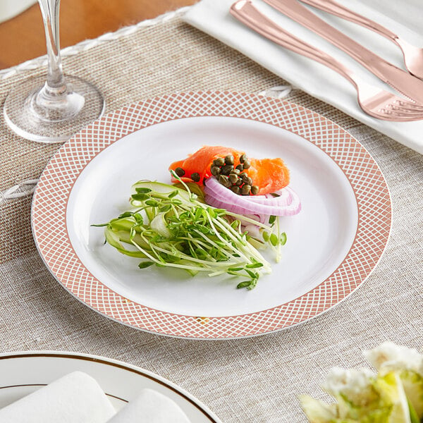A Visions white plastic plate with a rose gold lattice design, with a fork and knife on it.