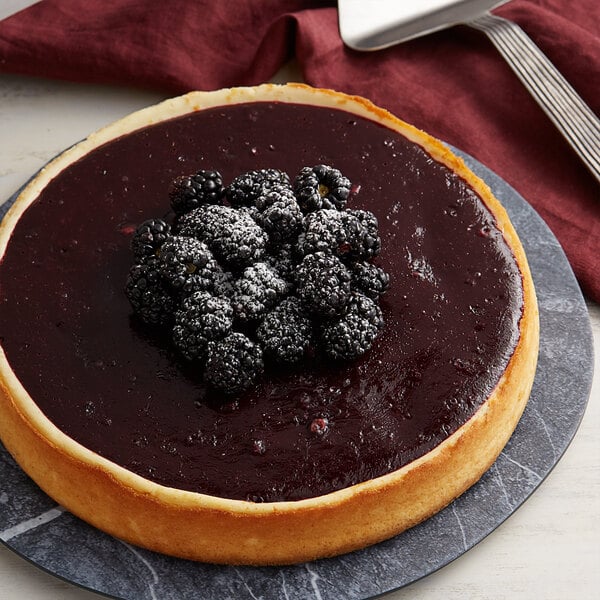 A cheesecake with Les Vergers Boiron blackberry puree and blackberries on top.