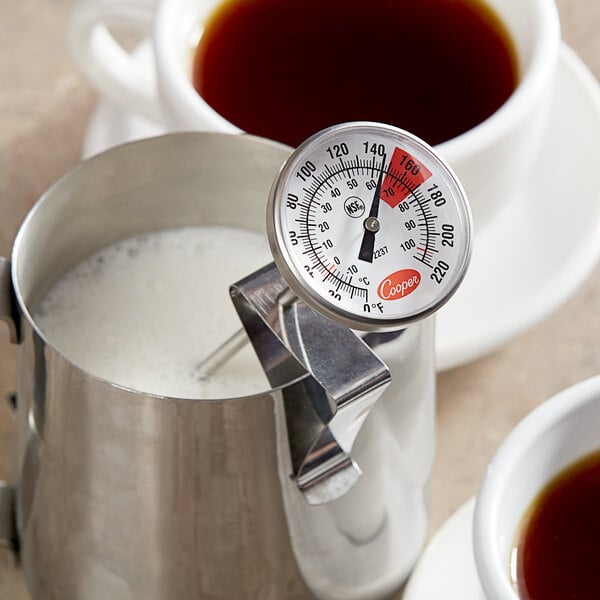 A Cooper-Atkins frothing thermometer in a cup of brown liquid.