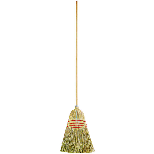 A Carlisle 5-stitch janitor corn broom with a wooden handle.