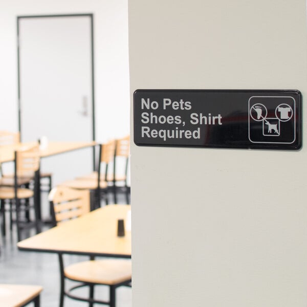 A black and white sign on a wall that says "No Pets, Shoes, and Shirt Required"