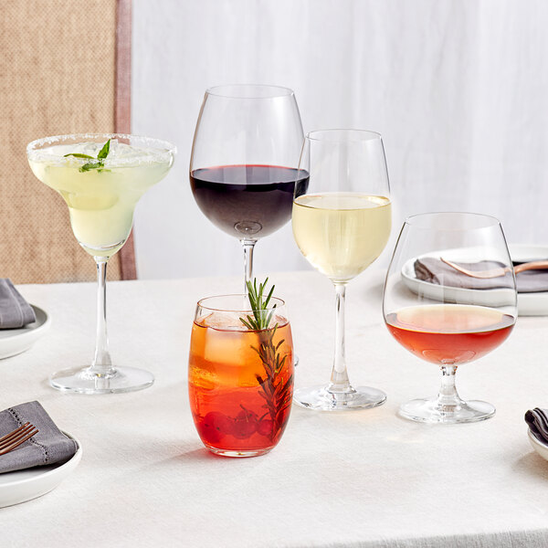 An Acopa Covella margarita glass with a drink and a sprig of rosemary on a table.