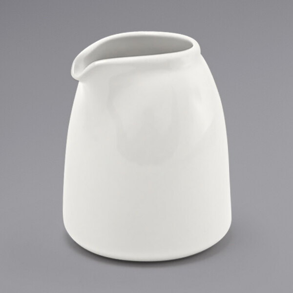 A Front of the House European white porcelain creamer with a spout and handle.