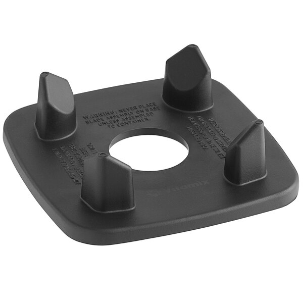 A black plastic square centering pad with four spikes.