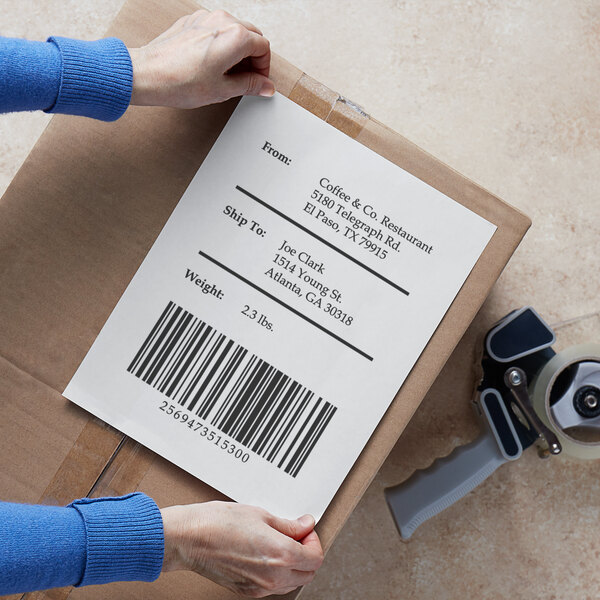 A person holding a cardboard box with a Lavex blank permanent label with a barcode on it.