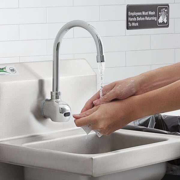 A person washing their hands under a Waterloo hands-free faucet.