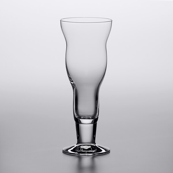 A clear Stolzle cocktail glass with a curved rim and a stem on a table.