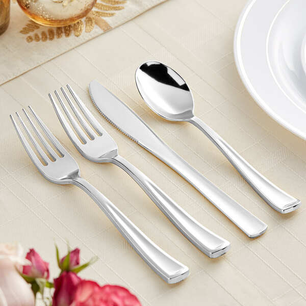 A Visions silver plastic cutlery set on a table with a white plate.
