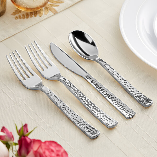 A close-up of a Visions Hammersmith silverware set with a spoon and knife on a white table.