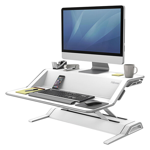 A Fellowes Lotus white sit/stand workstation with a keyboard and mouse on a table.