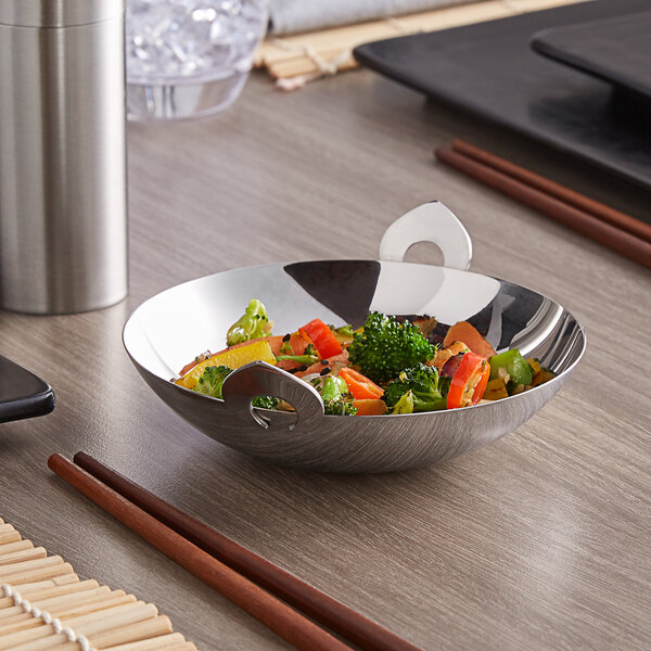 A Vollrath mini stainless steel wok filled with vegetables on a table.