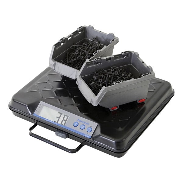 A black Brecknell portable utility bench scale on a table with a black and grey container on top.