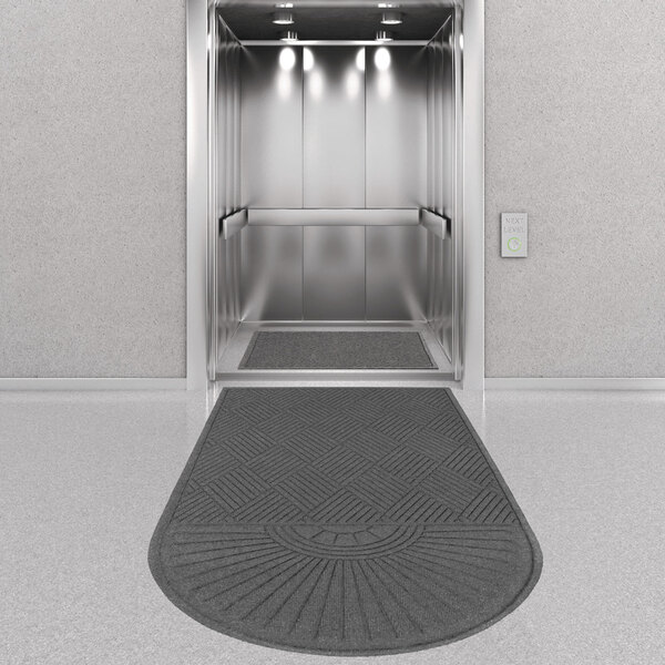 A charcoal Guardian EcoGuard diamond floor mat in front of an elevator.