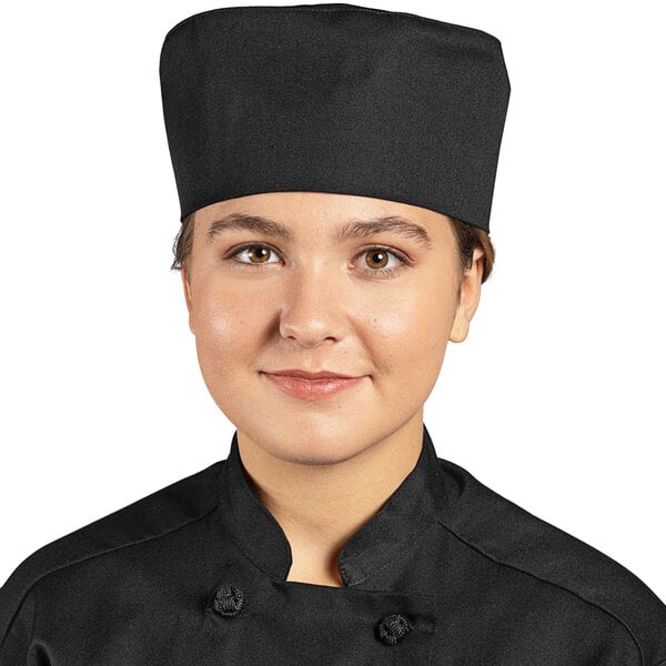A woman wearing a black Uncommon Chef skull cap in a professional kitchen.