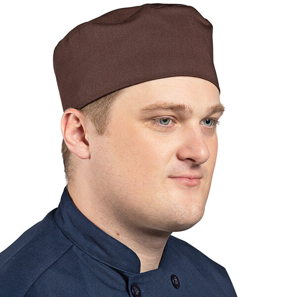 A man wearing a brown Uncommon Chef skull cap with hook and loop closure.