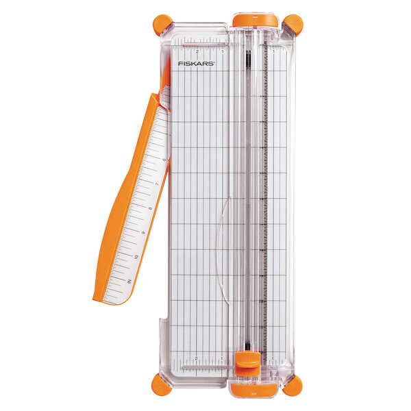 A Fiskars paper cutter with orange handles and a ruler on a white sheet.