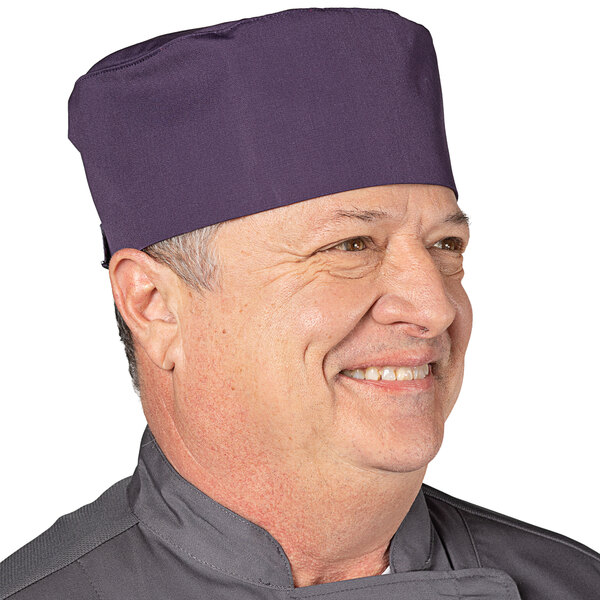 A man wearing a purple Uncommon Chef skull cap with a chef hat on top.